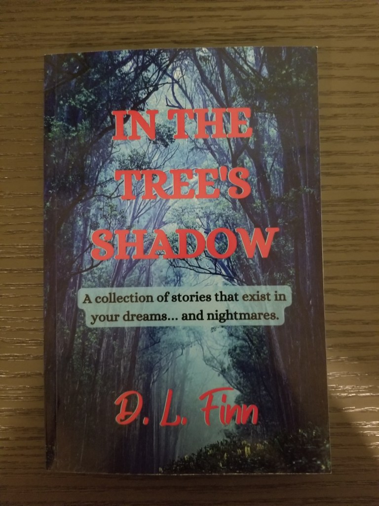 This is a photo of the front cover of the book In the Tree's Shadow. The front cover features trees in a fog and small clearing.