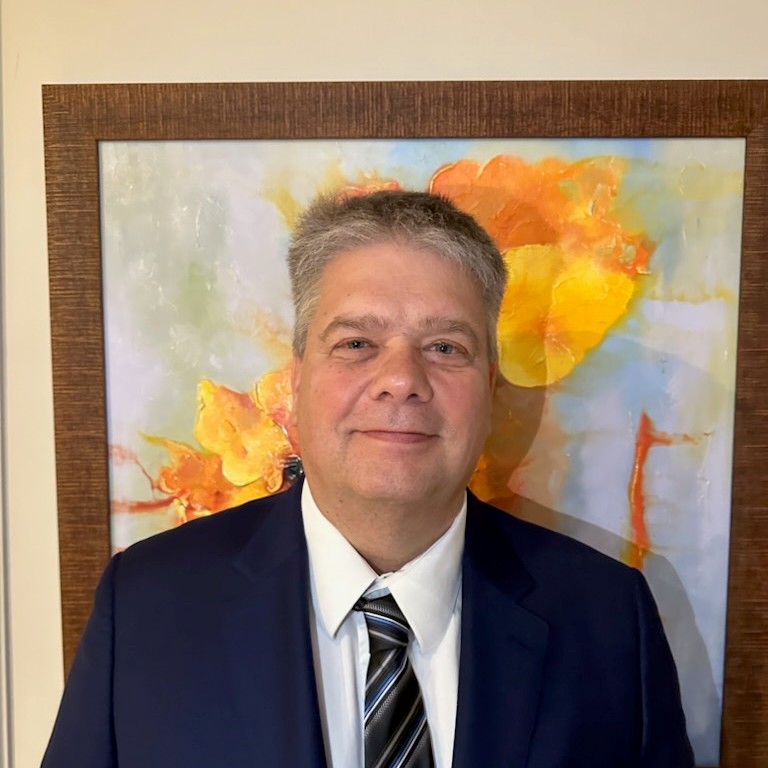 Me standing in front of a painting wearing a blue suit