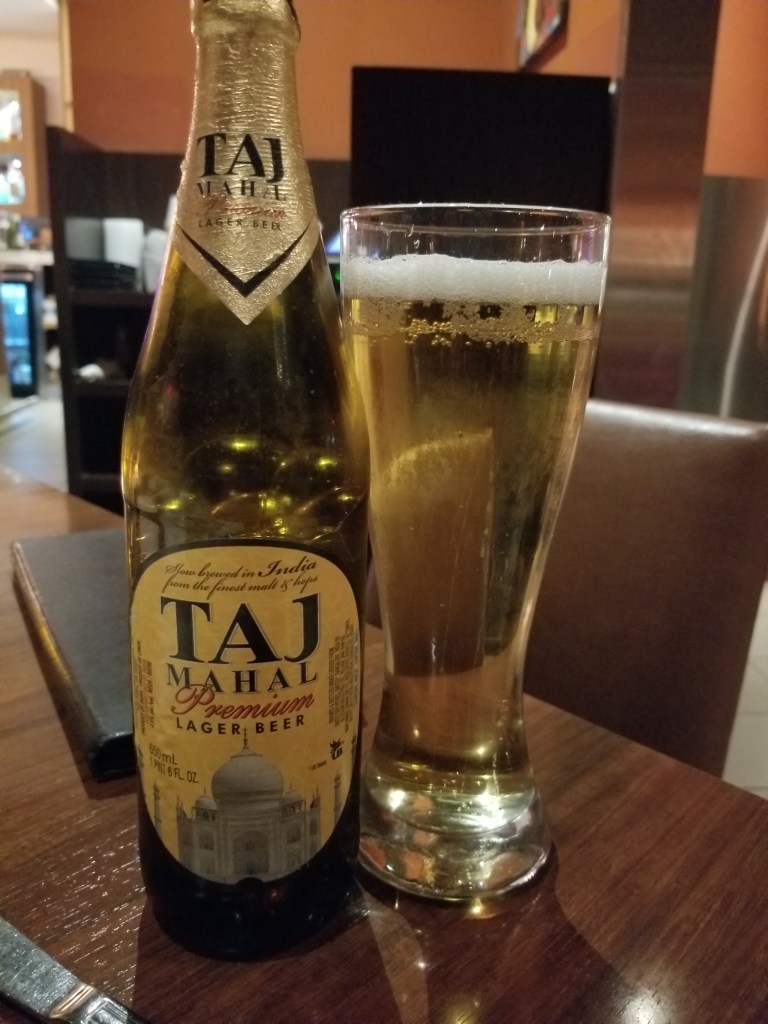 Bottle of Taja Mahal on left, glass with the beer on the right.