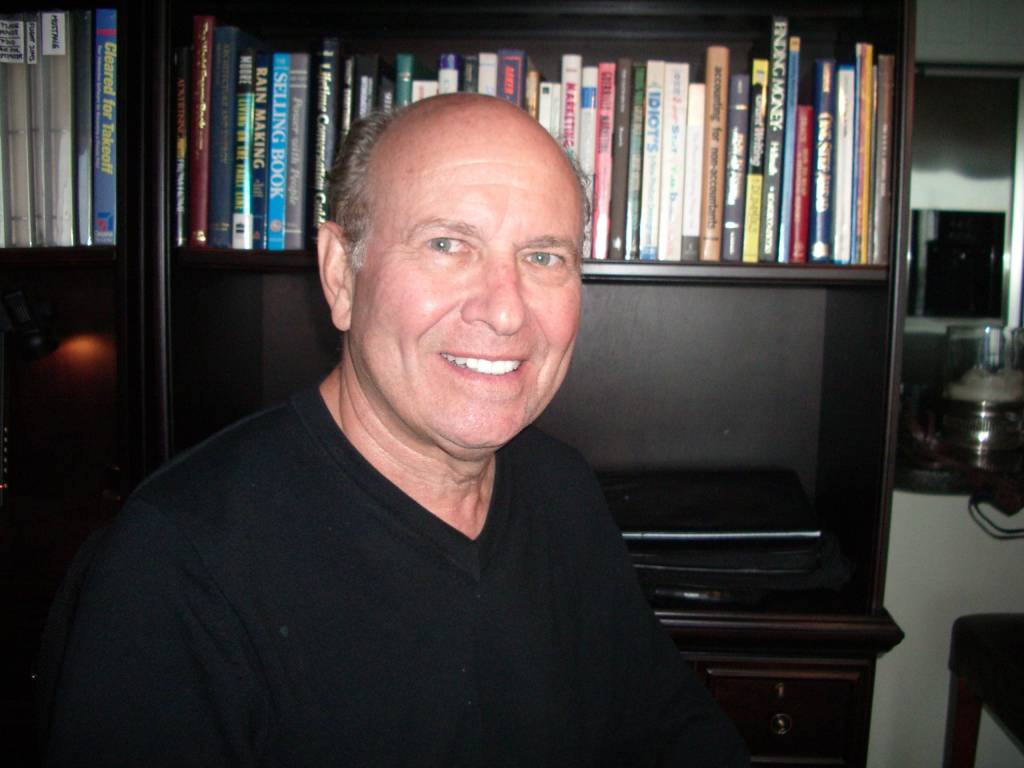 This is a photo of Jack Zimanck.in front of his bookshelf.