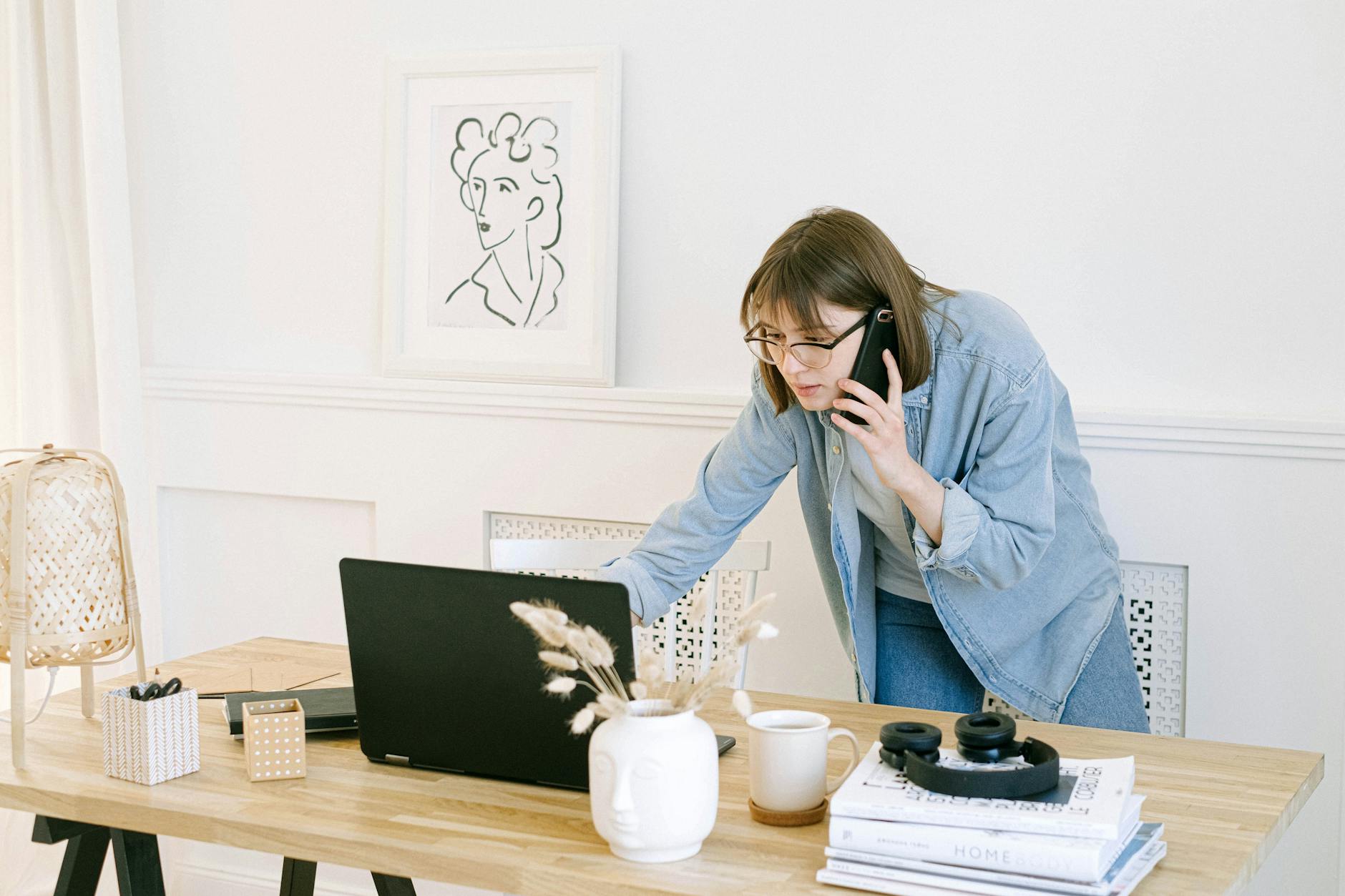 A woman on a phone with a laptop