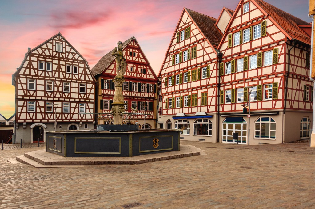 A town square surrounded by buildings. There is a statue in the middle.