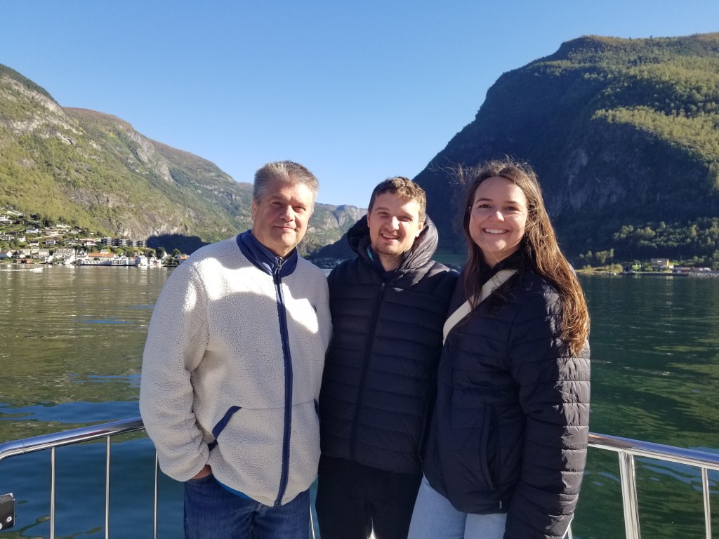 Three people standing on a boat on the fjord
