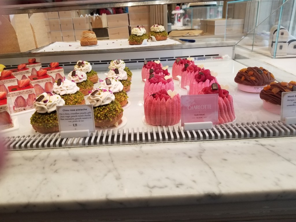 Glass counter featuring colorful pastries at Angelina, Paris, France.