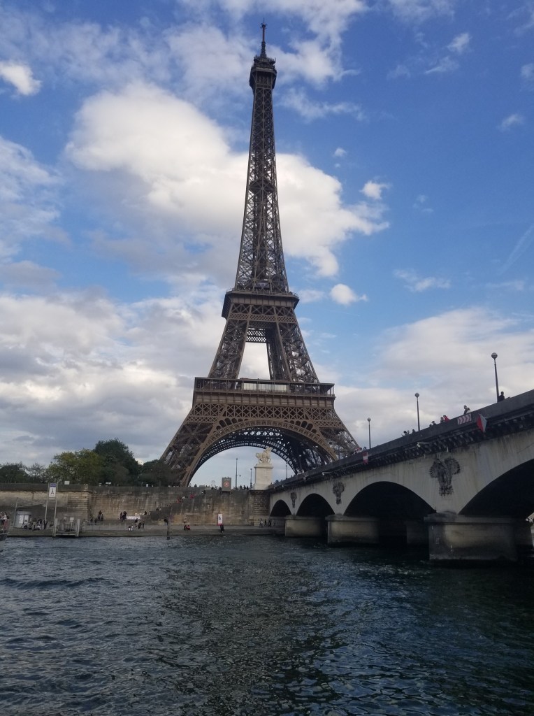 The photo features a bridge, the Seine River, with the Eiffel Tower in the background.