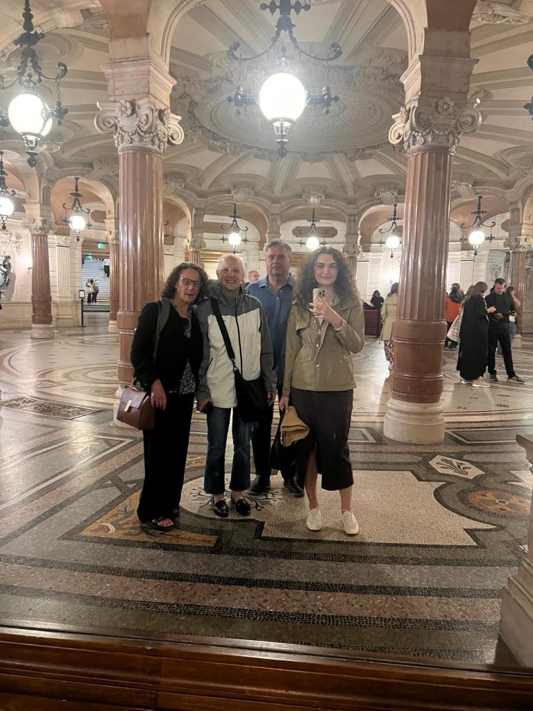Four people standing in front of a mirror in Palais Opéra Garnier. My daughter is taking a photo with her iPhone.
