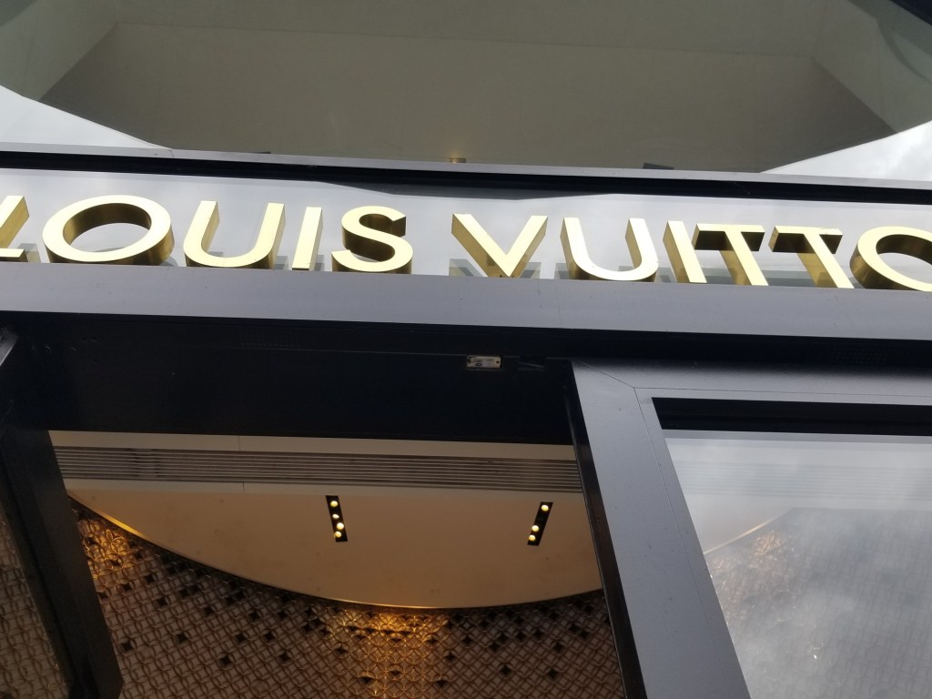The photo feature a sign saying Louis Vuitton, but it is partially cut off at the ends.