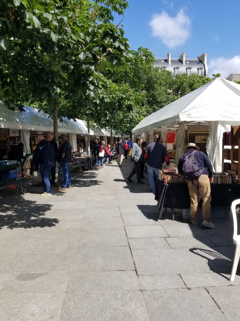 A row of stands where vendors are selling goods, art and other things.