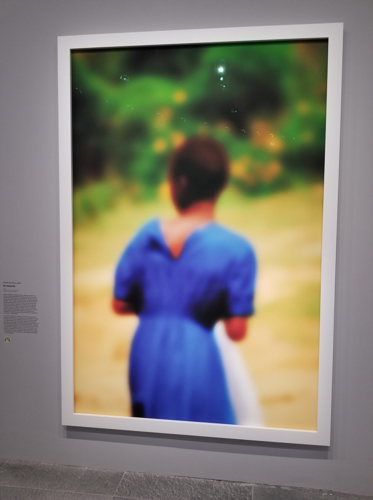 A blurry painting of a woman in a blue dress at the Musée de l'Orangerie.