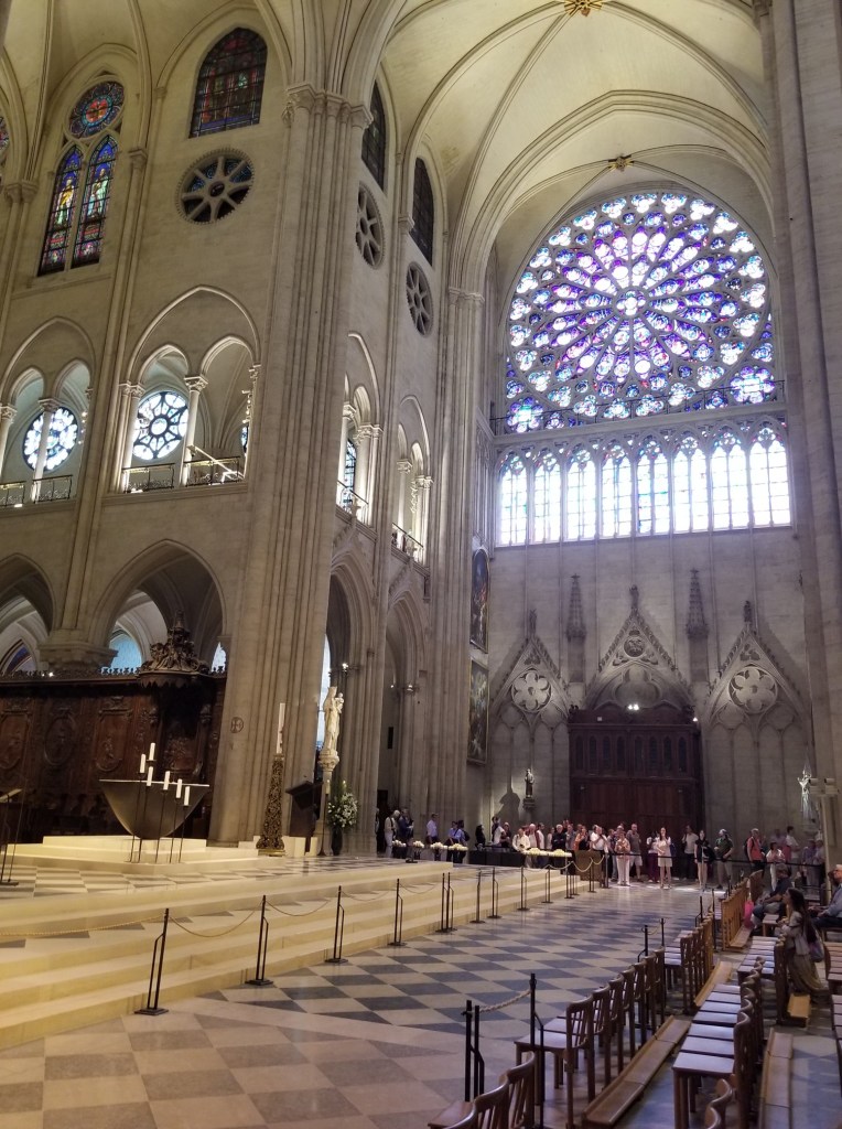 Inside the Notre Dame cathedral, across, with a large circular window in view.