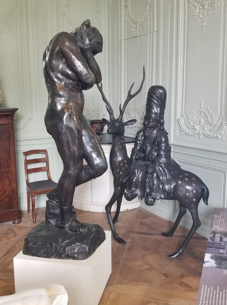 Inside the Rodin Museum; a naked woman and gnome with a tall hat riding a deer.