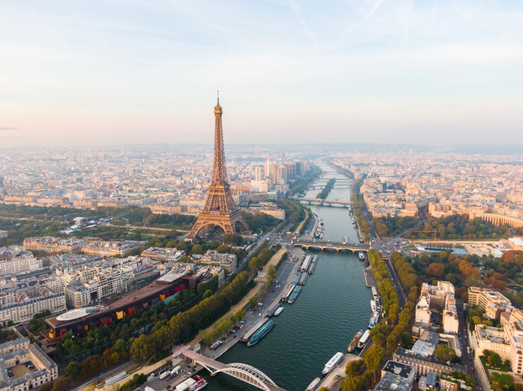 Establishing Aerial view of Paris Cityscape with Eiffel Tower and Seine River on sunrise, France. Landmark Monument as Famous Touristic Destination. Romantic Travel and Urban Skyline Panorama.