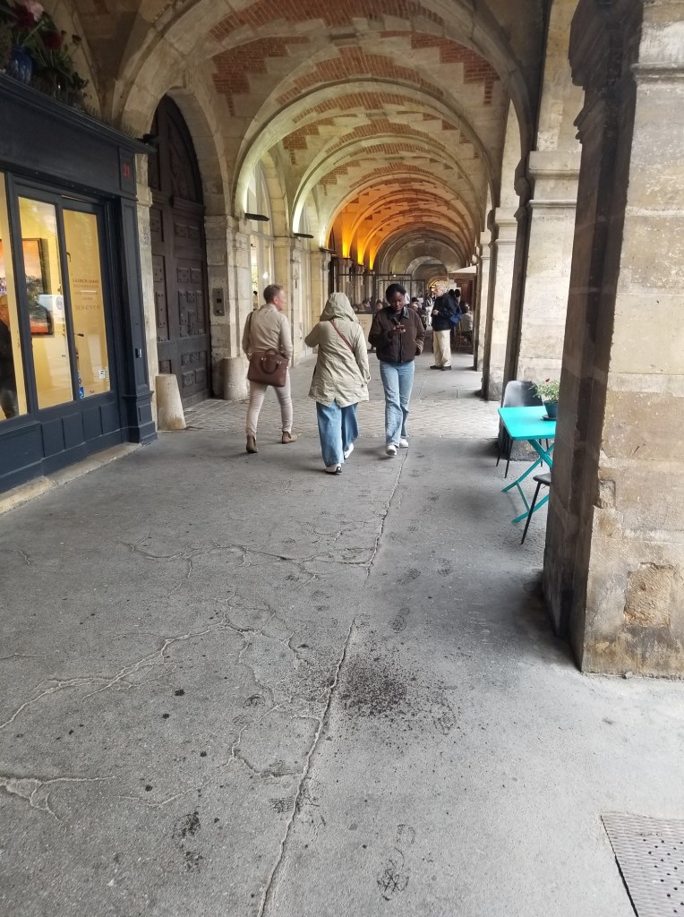 The sidewalk is covered by a decorated ceiling and enclosed by columns.