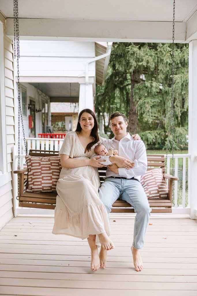 Three people sitting in a swing. Mother, father and the baby in the middle.