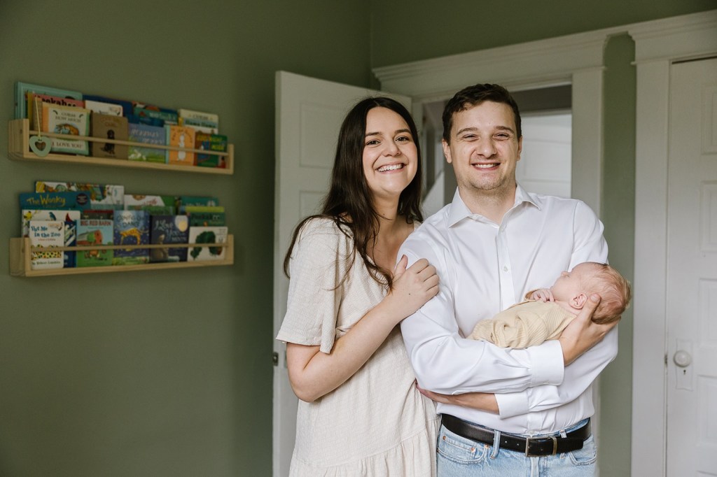 Mother and father standing on in a room holding the baby
