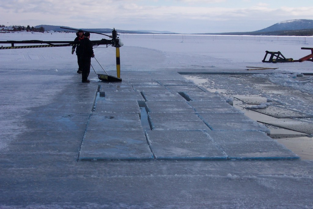 Photo of men with a machine cutting ice blocks.