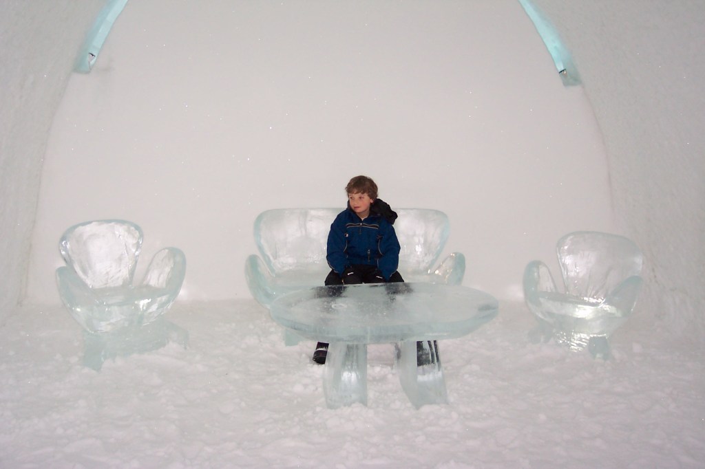 Photo of a beautiful table made of ice and two sofa chairs and one sofa, all made of ice.