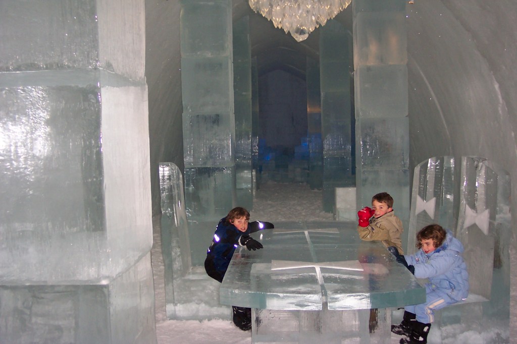 Photo is of a large ice table and ice chairs located in the middle of the lobby, which is filled with tall pillars made of ice.