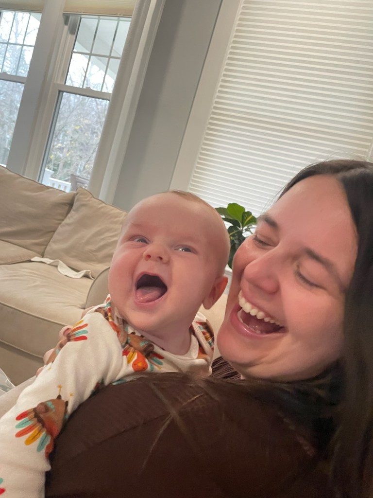 Ashley is holding 3 months old Jack and they are both smiling big.