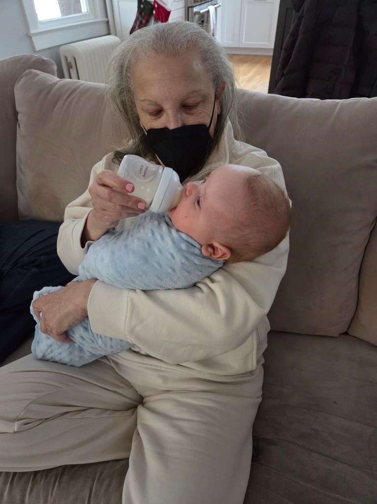 My wife Claudia is holding Jack, and she is holding a bottle of milk for him.