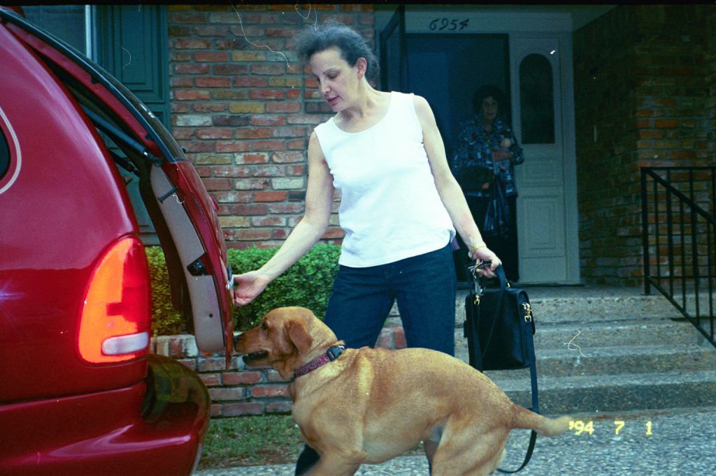 My wife, opening the trunk of our red van as Baylor, our Labrador is preparing to jump.