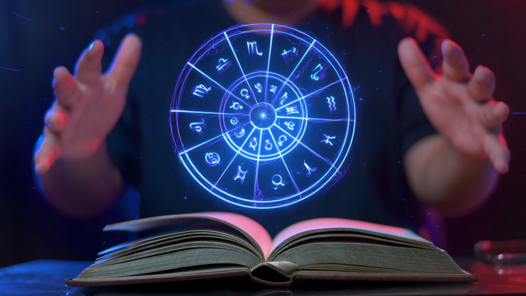 Zodiac signs and astrology with constellations, concepts, predictions, horoscopes, beliefs. Behind a circle of zodiac signs is man with his hands held around the circle zodiac signs as if it is a crystal ball for prediction.