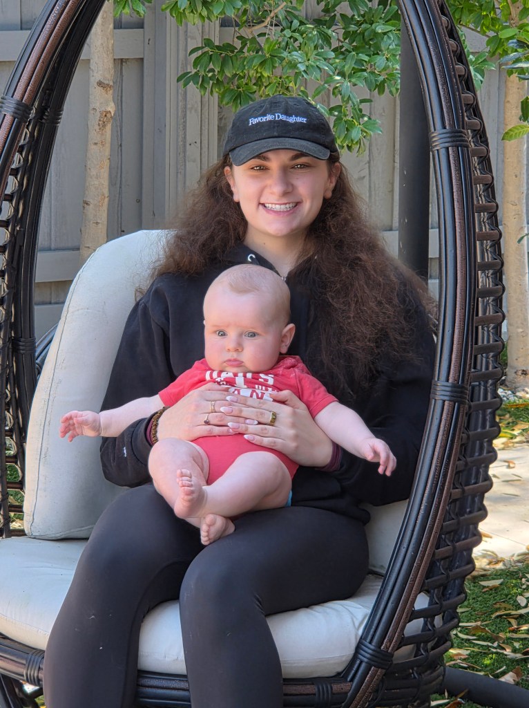 Our daughter is sitting in a swing holding baby Jack.