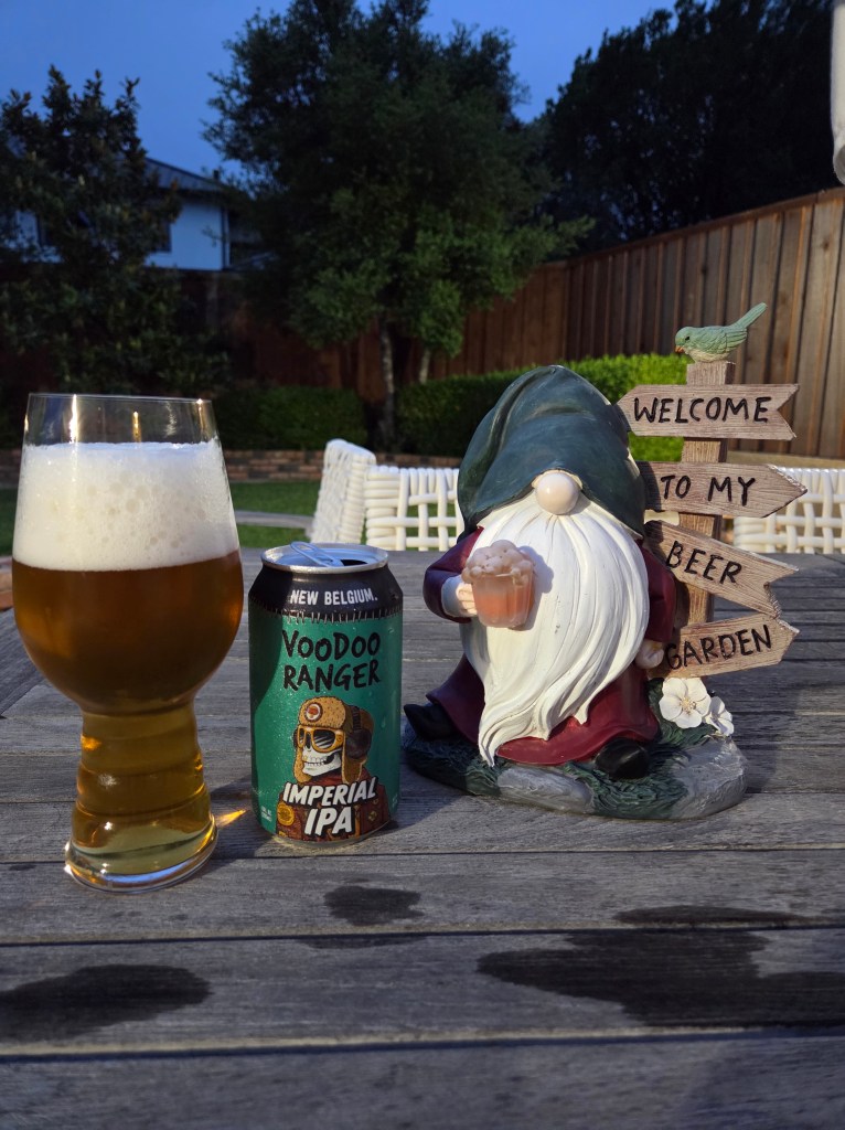 The photo shows a can of New Belgiums Voodoo Ranger Imperial IPA standing on our patio table, a gnome holding a beer and a sign saying, “Welcome to my beer garden.”