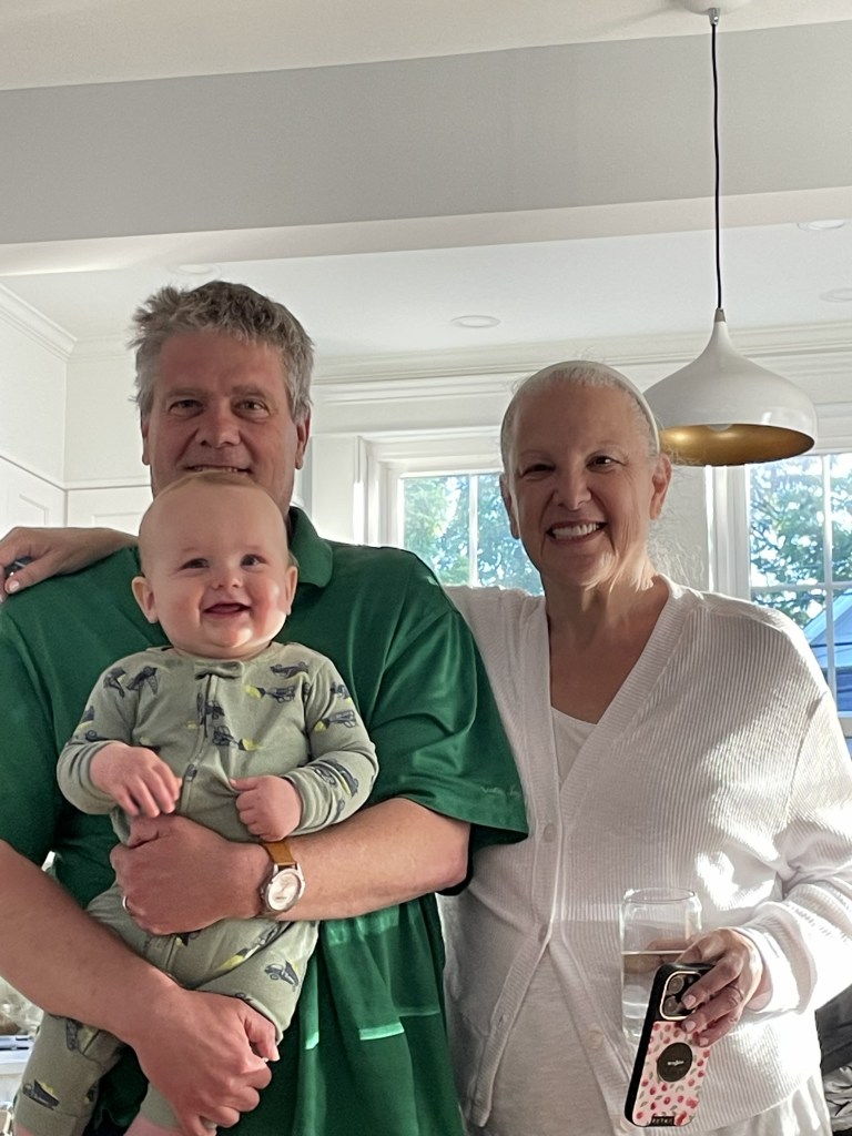 I am standing on the left wearing a green polo short. I am holding Jack who is smiling big. My wife Claudia is on the right.