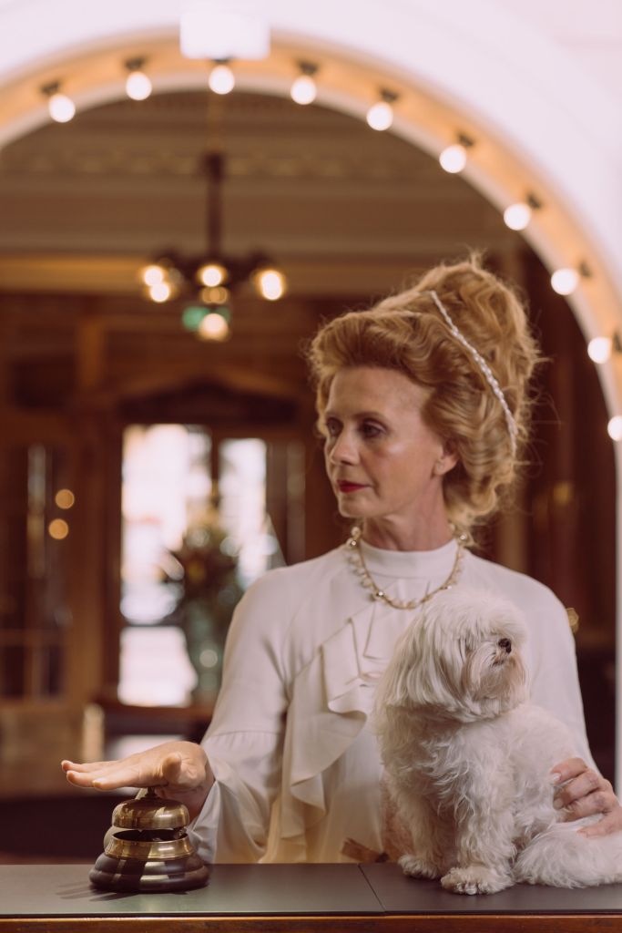 An old lady at the hotel reception. She has a small dog.