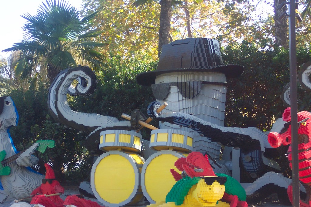 The big octopus has a black hat, black sunglasses, and is playing drums. He is surrounded by other musicians.