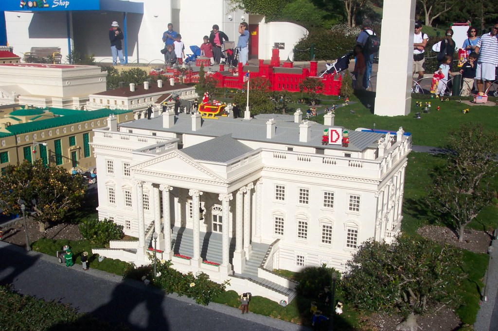 The White House is surrounded by greenery and other DC buildings.
